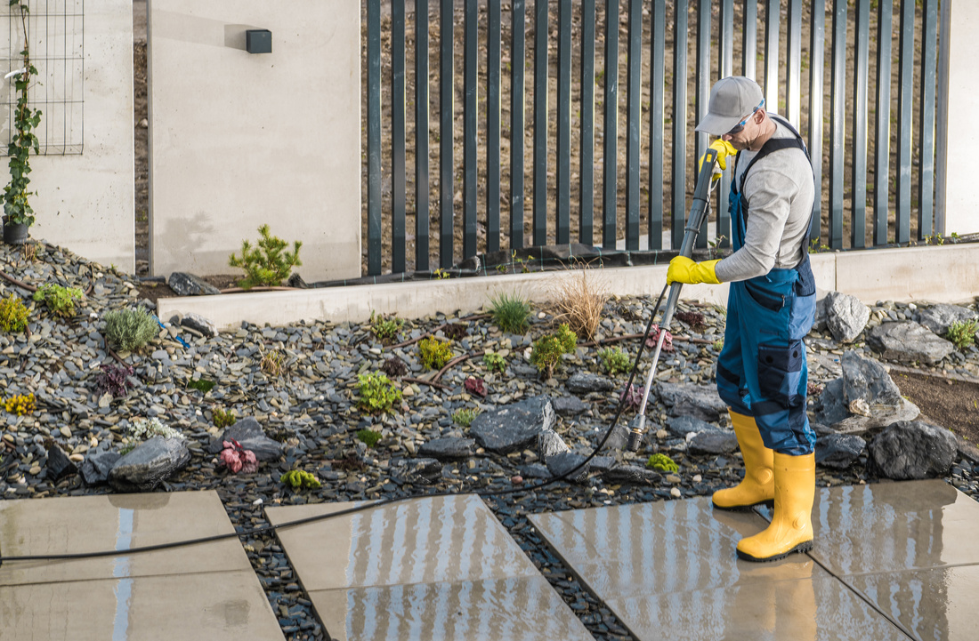 Man Pressure Washing Concrete Tiles